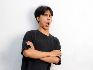 Siyah tişört giyen Asyalı genç bir adamın beyaz arka planda izole edilmiş bir şeye tepki göstermesi komik bir portredir..