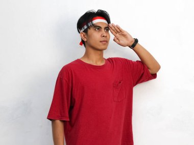 Asyalı gururlu bir gencin portresi, çarpıcı kırmızı bir gömlek ve Endonezya bayrağı bandı takıyor. 17 Ağustos 'ta Endonezya' nın bağımsızlık gününü kutluyor..