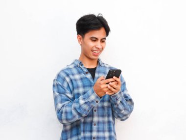 Stüdyoda akıllı telefonla poz veren Asyalı genç adam.