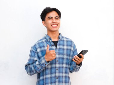 Stüdyoda akıllı telefonla poz veren Asyalı genç adam.