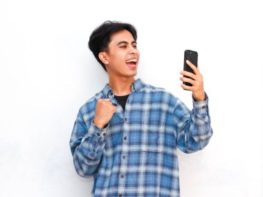 Stüdyoda akıllı telefonla poz veren Asyalı genç adam.