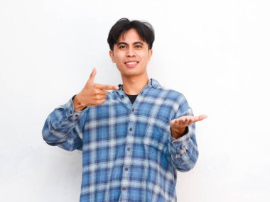 Stüdyodaki bir şeyi işaret eden Asyalı bir gencin portresi.