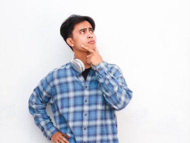 Kulaklıklı genç adam beyaz arka planda poz veriyor.