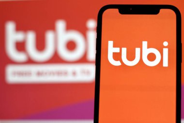 Tubi logosuna sahip akıllı telefonun yakın görüntüsü, Amerikan içerik platformu ve Fox Corporation 'a ait reklam destekli yayın servisi.