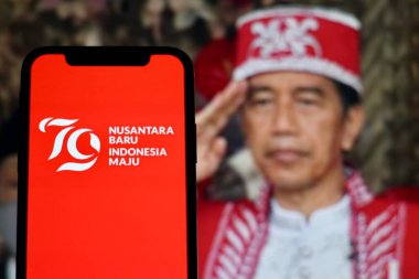 Wisma Negara 'daki Endonezya Cumhuriyeti' nin 79. yıldönümü için logolu akıllı telefon, Nusantara Baru Endonezya Maju, arka planda bulanık adam