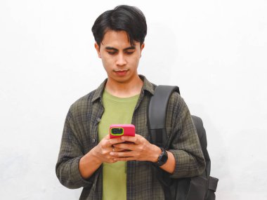 Beyaz arka planda akıllı telefon pozu veren yeşil flanel gömlekli Asyalı adam.    