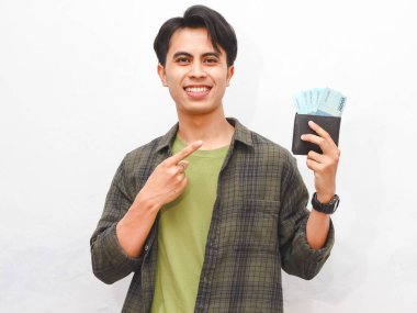 Yeşil flanel gömlekli Asyalı adam, beyaz arka planda parası olan bir cüzdan taşıyor.  