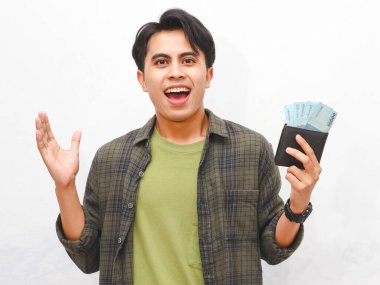 Yeşil flanel gömlekli Asyalı adam, beyaz arka planda parası olan bir cüzdan taşıyor.  