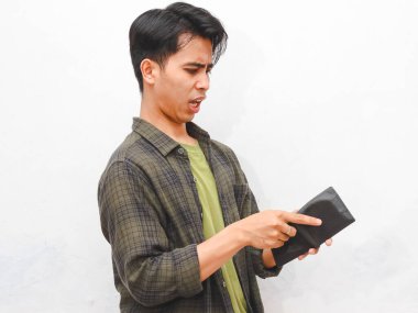 Beyaz arka planda boş cüzdan taşıyan yeşil fanila gömlekli zavallı Asyalı adam.