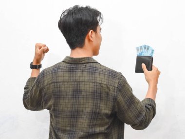 Yeşil flanel gömlekli Asyalı adam, beyaz arka planda parası olan bir cüzdan taşıyor.  