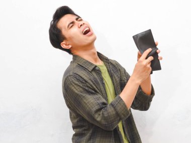 Beyaz arka planda boş cüzdan taşıyan yeşil fanila gömlekli zavallı Asyalı adam.