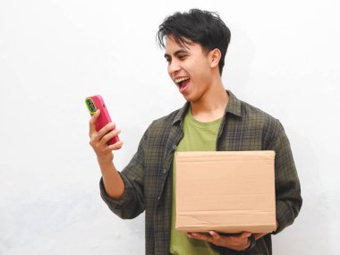 Yeşil flanel gömlekli Asyalı adam beyaz arka planda akıllı telefon tutuyor.  