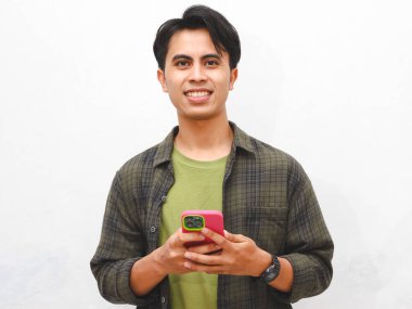 Yeşil flanel gömlekli Asyalı adam beyaz arka planda akıllı telefon tutuyor.  