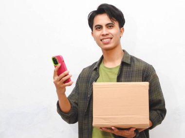 Yeşil flanel gömlekli Asyalı adam beyaz arka planda akıllı telefon tutuyor.  