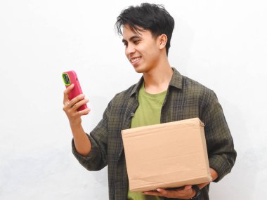 Yeşil flanel gömlekli Asyalı adam beyaz arka planda akıllı telefon tutuyor.  