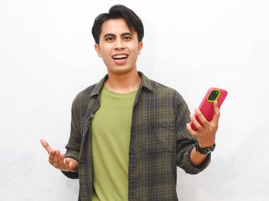 Yeşil flanel gömlekli Asyalı adam beyaz arka planda akıllı telefon tutuyor.  