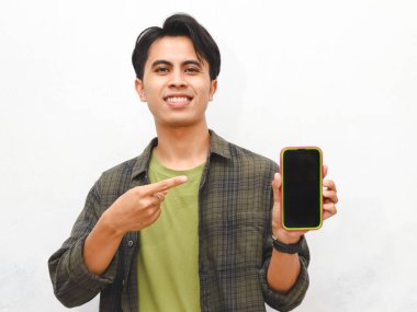Yeşil flanel gömlekli Asyalı adam beyaz arka planda akıllı telefon tutuyor.  