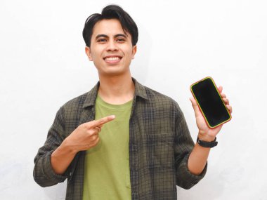 Yeşil flanel gömlekli Asyalı adam beyaz arka planda akıllı telefon tutuyor.  