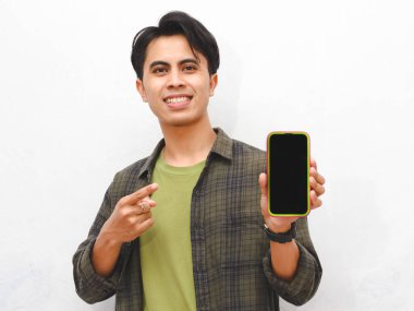 Yeşil flanel gömlekli Asyalı adam beyaz arka planda akıllı telefon tutuyor.  