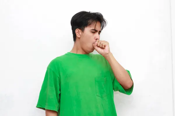 stock image Unhealthy adult Asian man in green t-shirt posing coughing on white background.