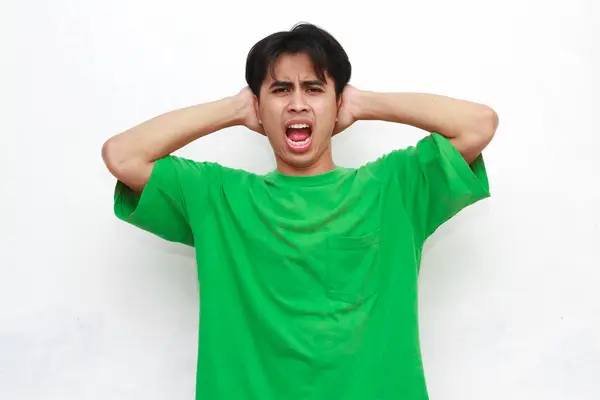 stock image Adult Asian man wearing green t-shirt posing with angry gesture with punching hand gesture on white background.