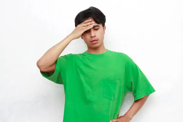 Stock image Sad adult Asian man in green t-shirt posing with stressed gesture on white background