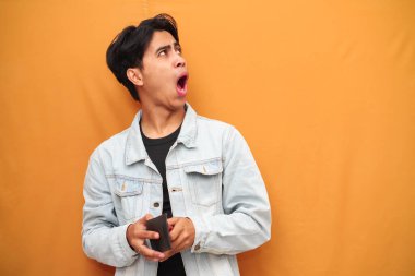 Asyalı adamın elinde cüzdan var. Komik bir yüz ifadesi var. Zavallı Asyalı adamın elinde boş bir cüzdan var.