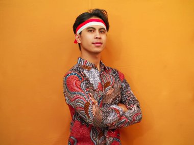 Batik tişörtlü yakışıklı Endonezyalı adam 17 Ağustos 'ta Endonezya Bağımsızlık Günü' nü kutluyor, kendinden emin bir şekilde poz veriyor ve kameraya bakıyor.