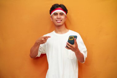 Endonezyalı adam 17 Ağustos 'ta Endonezya Bağımsızlık Günü' nü kutluyor. Endonezyalı adam elinde akıllı telefon tutarken parmağıyla işaret ediyor.