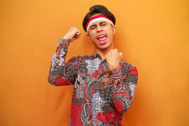 Batik tişörtlü Endonezyalı adam 17 Ağustos 'ta Endonezya Bağımsızlık Günü' nü kutluyor. Gururlu bir şekilde poz veriyor, zafer ve başarıyı kutluyor. Çok heyecanlı.