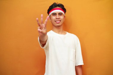 Mutlu bir Endonezyalı, sarı arka planda parmaklarıyla birden beşe kadar sayarak poz verir. Endonezya 'nın 17 Ağustos' taki bağımsızlık gününü kutlama konsepti.