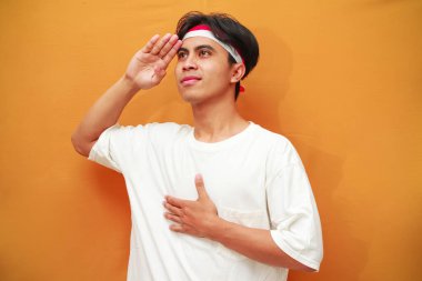 17 Ağustos 'ta Endonezya' nın bağımsızlığını kutlayan mutlu Endonezyalı adam, gururlu ve sarı arka planda izole edilmiş bir şekilde göğsüne sarıldı.