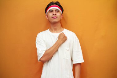 17 Ağustos 'ta Endonezya' nın bağımsızlığını kutlayan mutlu Endonezyalı adam, gururlu ve sarı arka planda izole edilmiş bir şekilde göğsüne sarıldı.