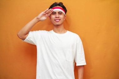 17 Ağustos 'ta Endonezya' nın bağımsızlığını kutlayan mutlu Endonezyalı adam, gururlu ve sarı arka planda izole edilmiş bir şekilde göğsüne sarıldı.