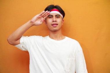 17 Ağustos 'ta Endonezya' nın bağımsızlığını kutlayan mutlu Endonezyalı adam, gururlu ve sarı arka planda izole edilmiş bir şekilde göğsüne sarıldı.