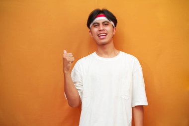 Mutlu bir Endonezyalı, sarı arka planda başparmağını yukarı kaldırarak poz verir. Endonezya 'nın 17 Ağustos' taki bağımsızlık gününü kutlama konsepti.