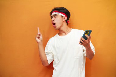 Endonezyalı bir adam Endonezya Bağımsızlık Günü 'nü 17 Ağustos' ta kutluyor. Elinde cep telefonuyla poz veriyor..