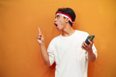 Endonezyalı bir adam Endonezya Bağımsızlık Günü 'nü 17 Ağustos' ta kutluyor. Elinde cep telefonuyla poz veriyor..