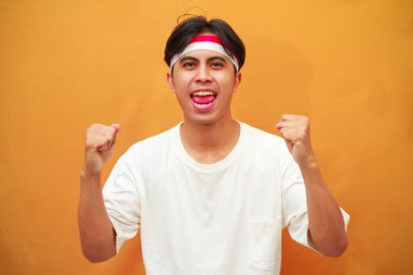 17 Ağustos 'ta Endonezya' nın bağımsızlığını kutlayan mutlu Endonezyalı adam sarı arka planda izole edilmiş zaferi haykırıyor ve kutluyor.