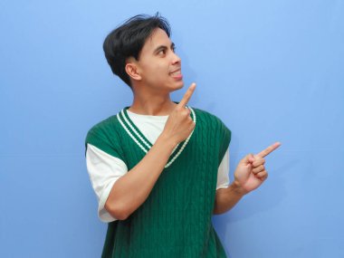 Asyalı bir adamın boş bir telif alanını işaret eden portresi heyecanlı mutlu yüzle izole edilmiş mavi arkaplan.