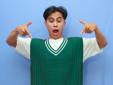 Asyalı bir adamın boş bir telif alanını işaret eden portresi heyecanlı mutlu yüzle izole edilmiş mavi arkaplan.