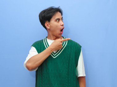 Asyalı bir adamın mavi arka planda izole edilmiş bir şekilde parmak gösteren komik bir portresi.