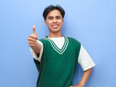 Bir şeyim yok. Mutlu, heyecanlı Asyalı adamın portresi parmaklarıyla onay veriyor, gülümsüyor, iyi olduğunu gösteriyor, mavi stüdyo arka planında izole edilmiş. Kendine güvenen genç iyidir.