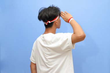 Beyaz tişörtlü Endonezyalı adam ve Endonezya bayrağı gururla ve selam veriyor, Endonezya bağımsızlık günü konsepti