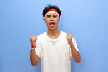 heyecanlı Endonezyalı beyaz gömlekli adam ve Endonezya bayrağı sıkılmış yumruğunu sallarken gururla bağırıyor zafer ve başarıyı kutluyor, Endonezya bağımsızlık günü konsepti