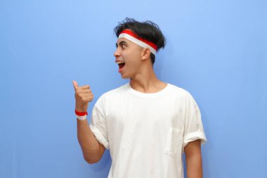 Beyaz tişörtlü Endonezyalı adam ve Endonezya bayrağı boş yere mutlu yüzüyle işaret ediyor, Endonezya bağımsızlık günü konsepti.