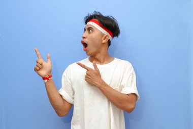 Beyaz tişörtlü Endonezyalı adam ve Endonezya bayrağı boş yere mutlu yüzüyle işaret ediyor, Endonezya bağımsızlık günü konsepti.