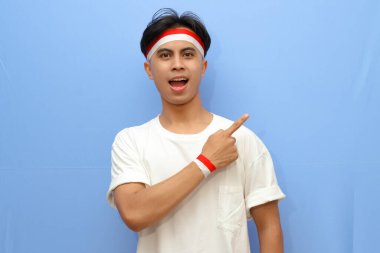 Beyaz tişörtlü Endonezyalı adam ve Endonezya bayrağı boş yere mutlu yüzüyle işaret ediyor, Endonezya bağımsızlık günü konsepti.