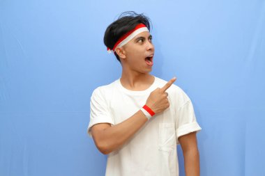 Beyaz tişörtlü Endonezyalı adam ve Endonezya bayrağı boş yere mutlu yüzüyle işaret ediyor, Endonezya bağımsızlık günü konsepti.