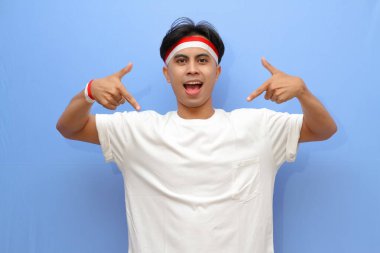 Beyaz tişörtlü Endonezyalı adam ve Endonezya bayrağı boş yere mutlu yüzüyle işaret ediyor, Endonezya bağımsızlık günü konsepti.